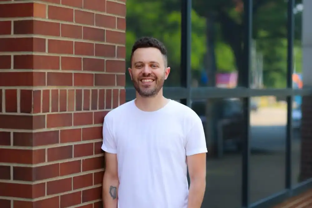 Ryan Daley leans a shoulder against brick wall in downtown Erie