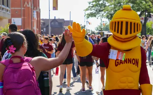 Mascot Victor E Knight, high-fiving a student at the IgKnight Activies Fair