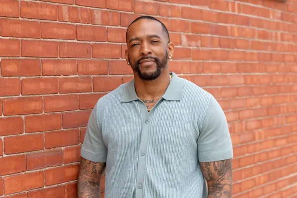 Portrait photograph of Ashton Jones posed against a brick wall