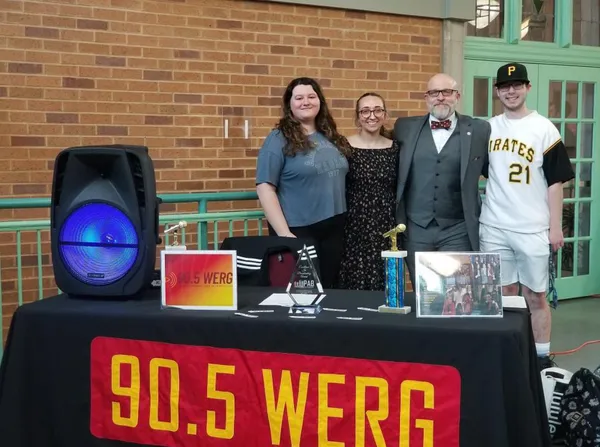 Student DJs from ˶ƽ's radio station, 90.5 WERG, stand with Dr. Iwanenko behind a table with equipment on it smiling.