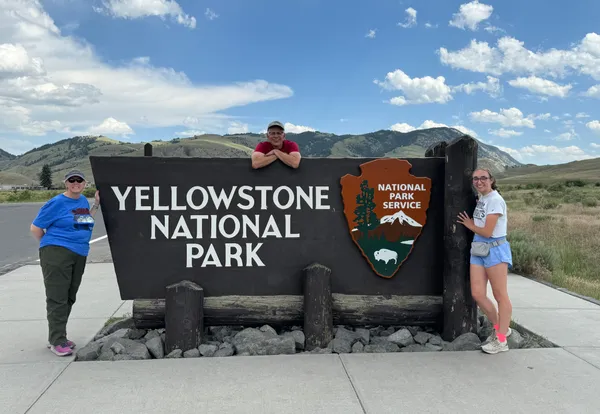 Madeline Emerson, Dr. Ropski and Mrs. Ropski around the Yellowstone National Park sign.