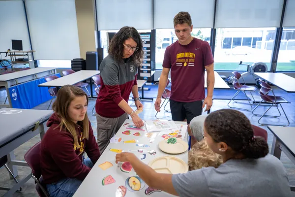 ڰ nutrition students working on a project with their professor