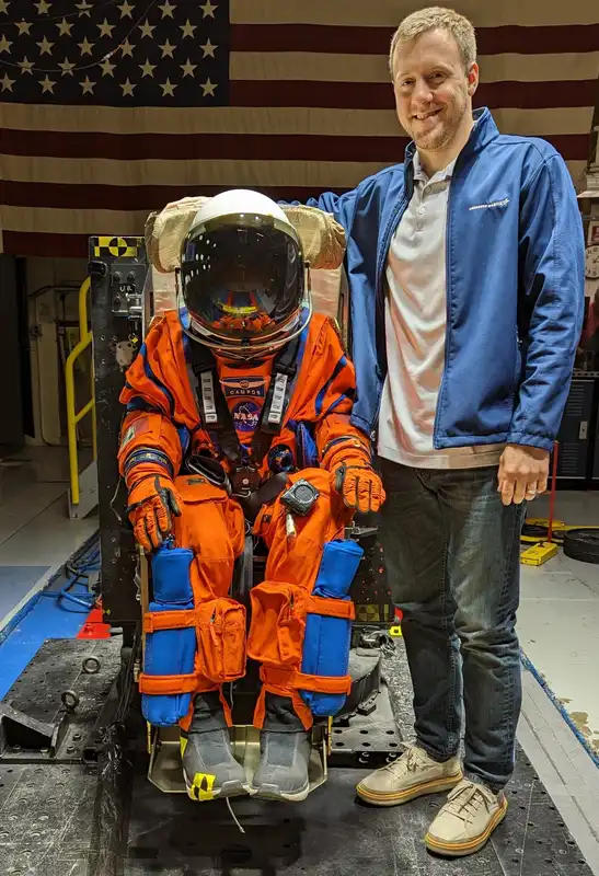Gannon University alum CJ Kennett stands next to a NASA Spacesuit used on the Artemis II launch