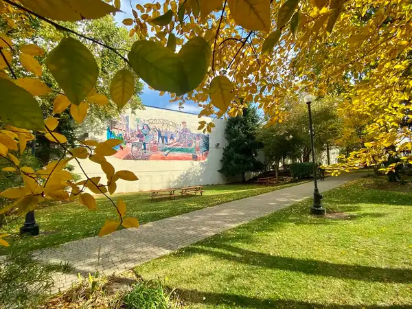 Image of the ˶ƽ Mural, located on Aj's way surrounded by fall leaves