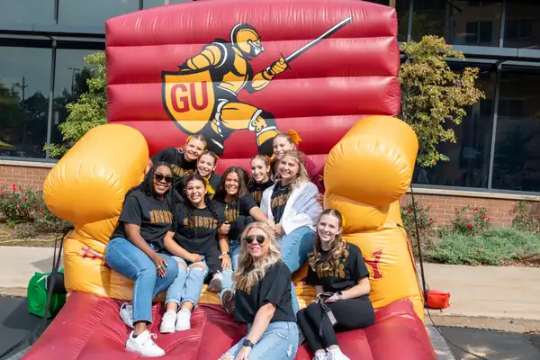 Students sitting on inflatable 91 chair during homecoming.