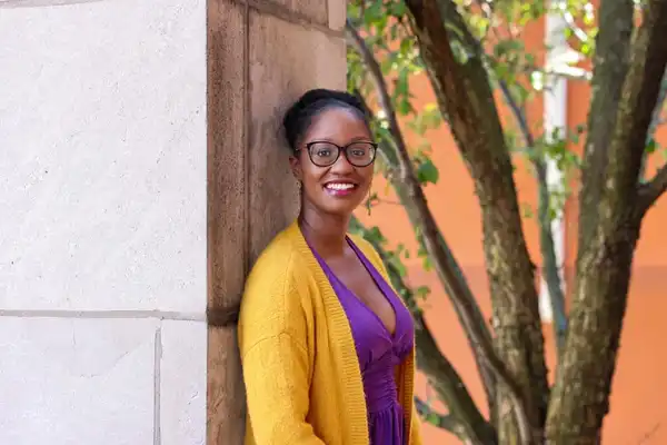 Damali stand with her back to a wall