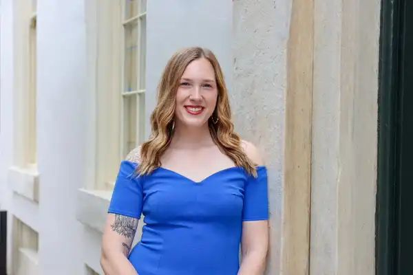 Kaitlyn smiles at the camera, leaning against a wall