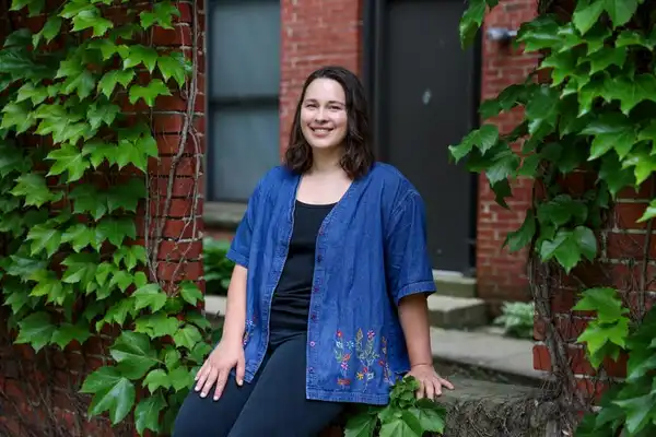 Hannah Rhodes smiles at the camera from a relaxed, seated position