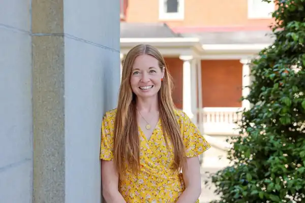 Amber Stilwell stands leaning against a wall and looking at the camera in downtown Erie
