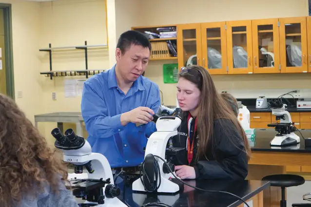Professor and student looking through a microscope in a lab.