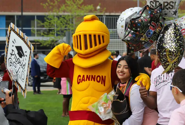 Victor posing with a recently graduated student with balloons and flowers