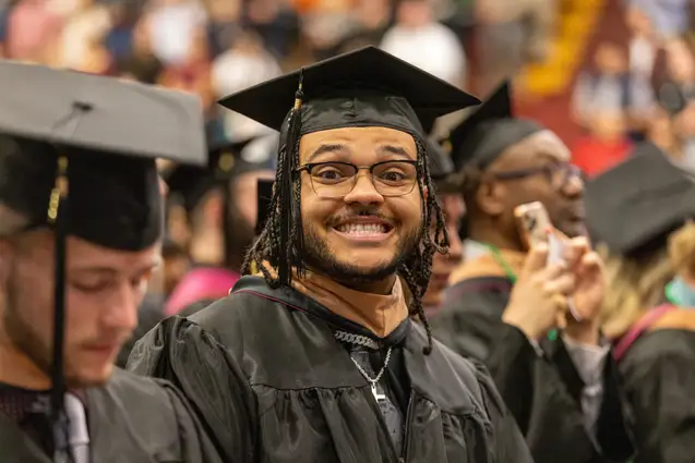 Student in cap and gown at Commencement ceremony.