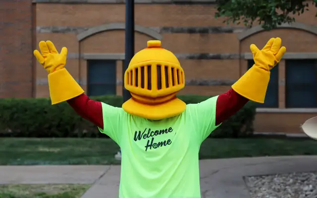 Victor E Knight on move in day in front of North Hall with a shirt reading welcome home