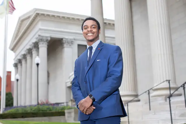 Student in a suit standing in front of the Erie County Court House