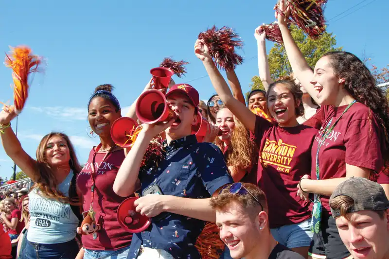 Students cheering for the football team during homecoming weekend