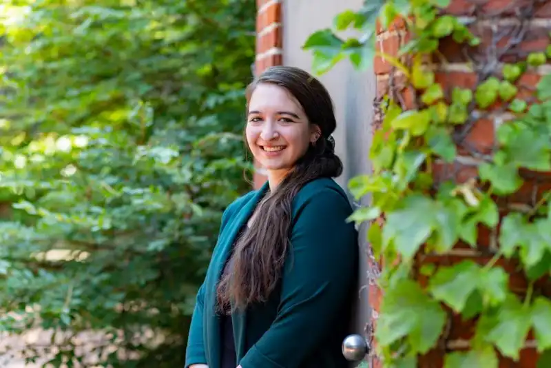 Alexandria poses against a brick wall, smiling