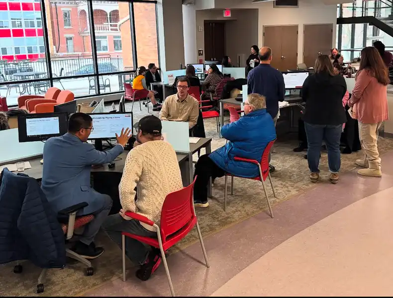 Inside Nash Library, groups of faculty meet in groups around computers to view presentations.