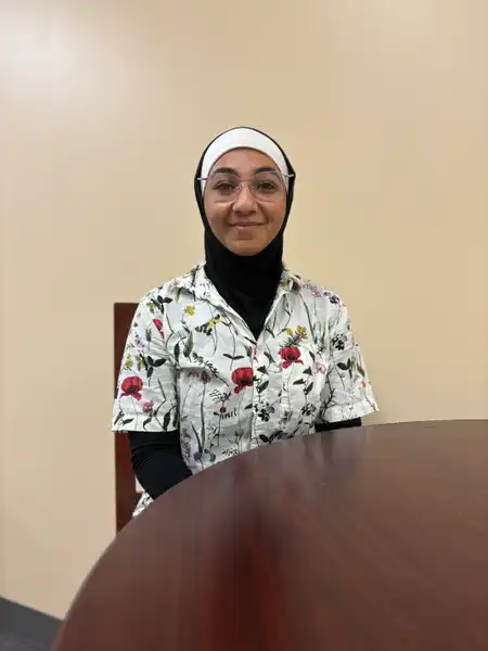 Zainab sits, smiling at the camera