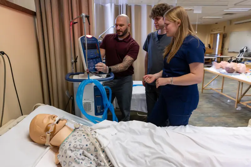 The program chair of ������Ƶ's respiratory care program and students in the program stand behind a mannequin hooked up to a ventilator