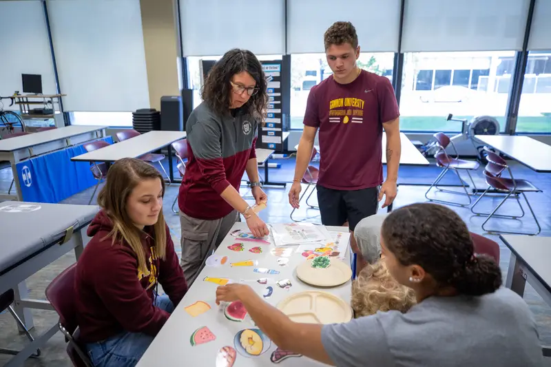 ������Ƶ nutrition students working on a project with their professor