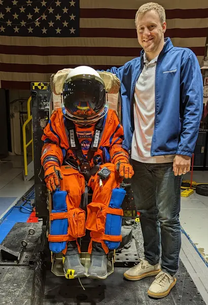 Gannon University alum CJ Kennett stands next to a NASA Spacesuit used on the Artemis II launch
