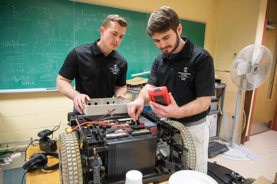 Two students examining a robot with a multimeter