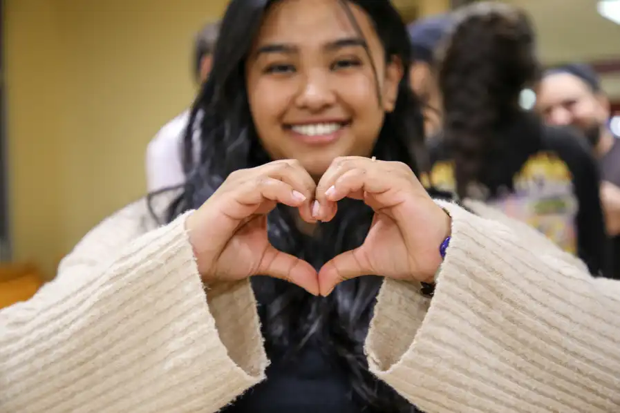 91 student making a heart symbol with hands.