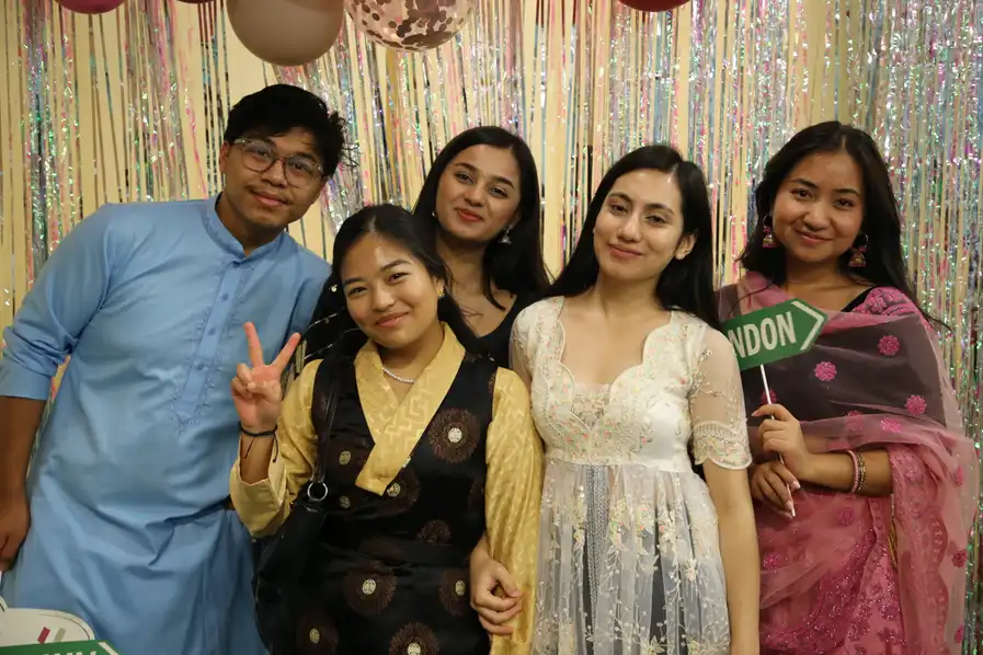5 students posing in front of a photo wall